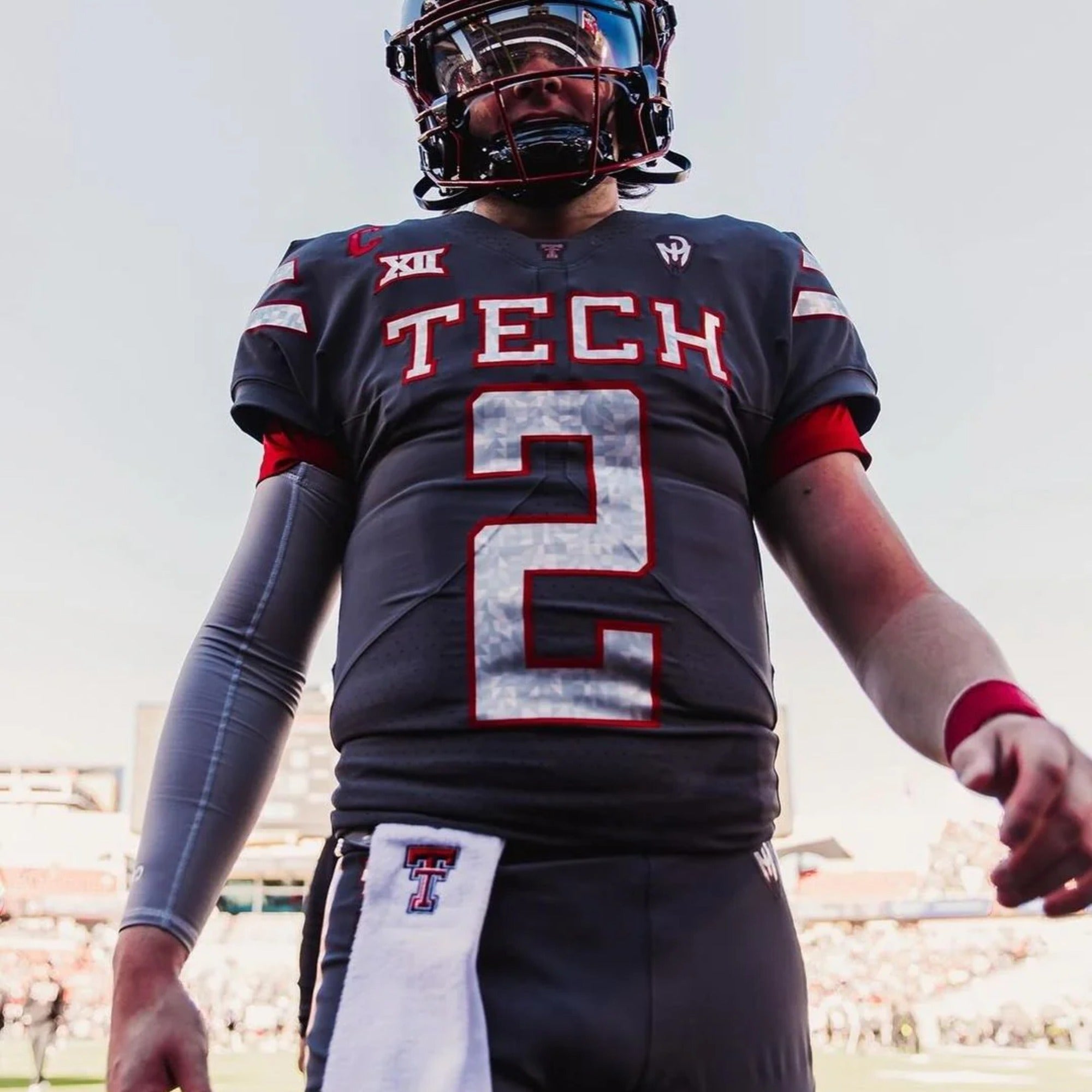 FBS football player wearing the Vettex Football Grip Sleeve on the sideline — patented grip-enhancing textile, NCAA and NFHS legal, used at 40+ FBS programs